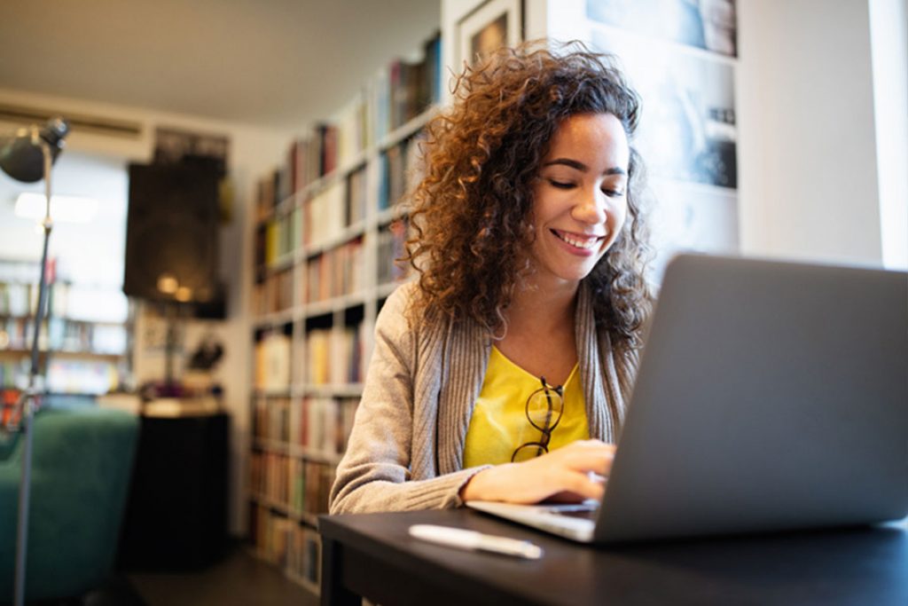 woman sitting at a desk typing on a laptop