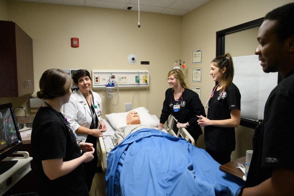 nursing students gathered around practice manikin