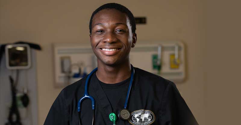 ABSN student standing in sim lab smiling