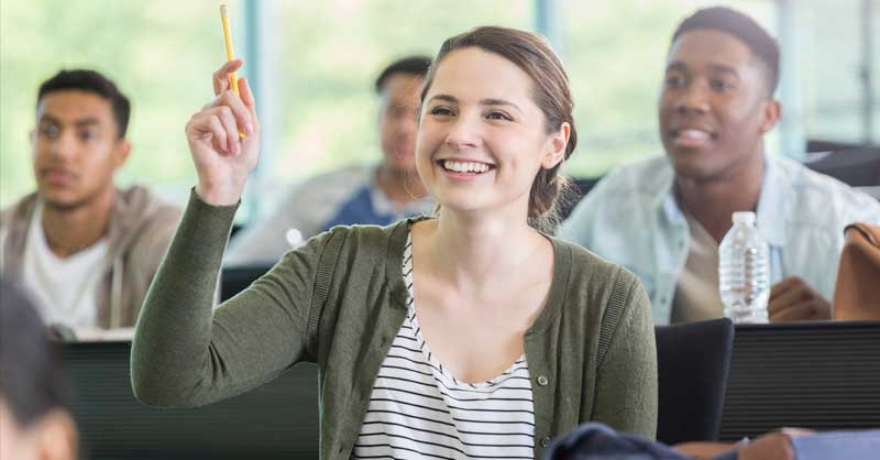 woman sitting in class raising her hand