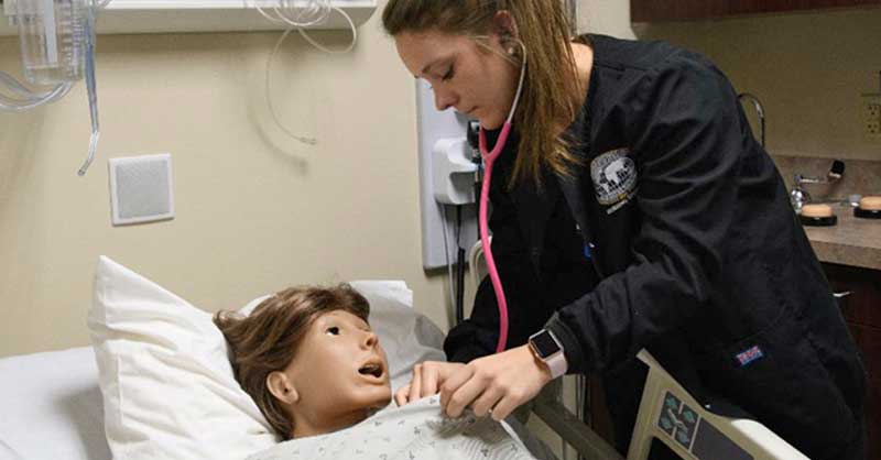 nursing student working with sim manikin