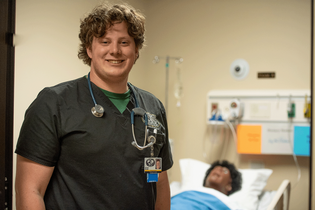 nursing student smiling with manikin in background