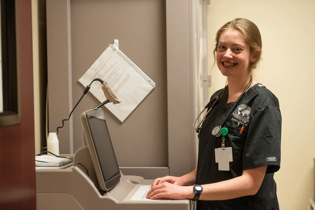 portrait of nursing student smiling while typing on computer